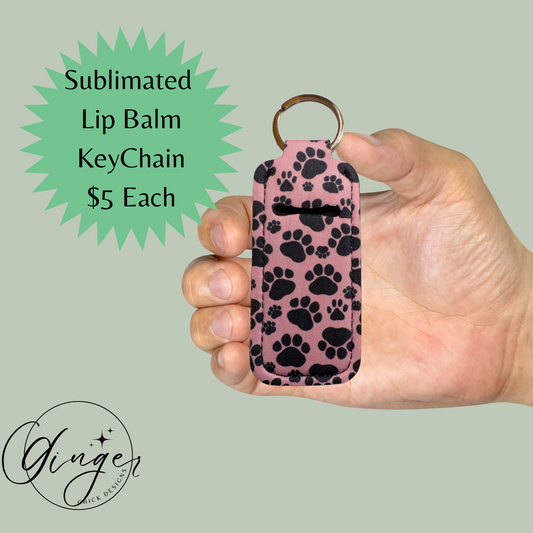 Hand holding a pink lip balm keychain with black paw prints on a light green background.