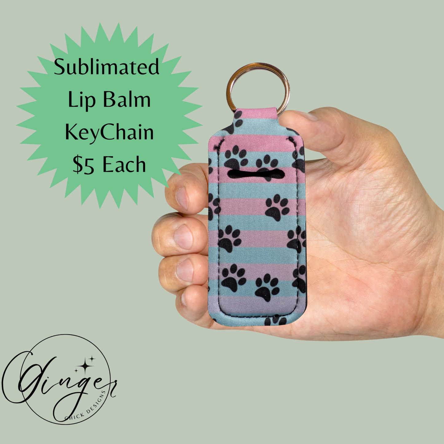 Hand holding a lip balm keychain with paw prints against a light green background