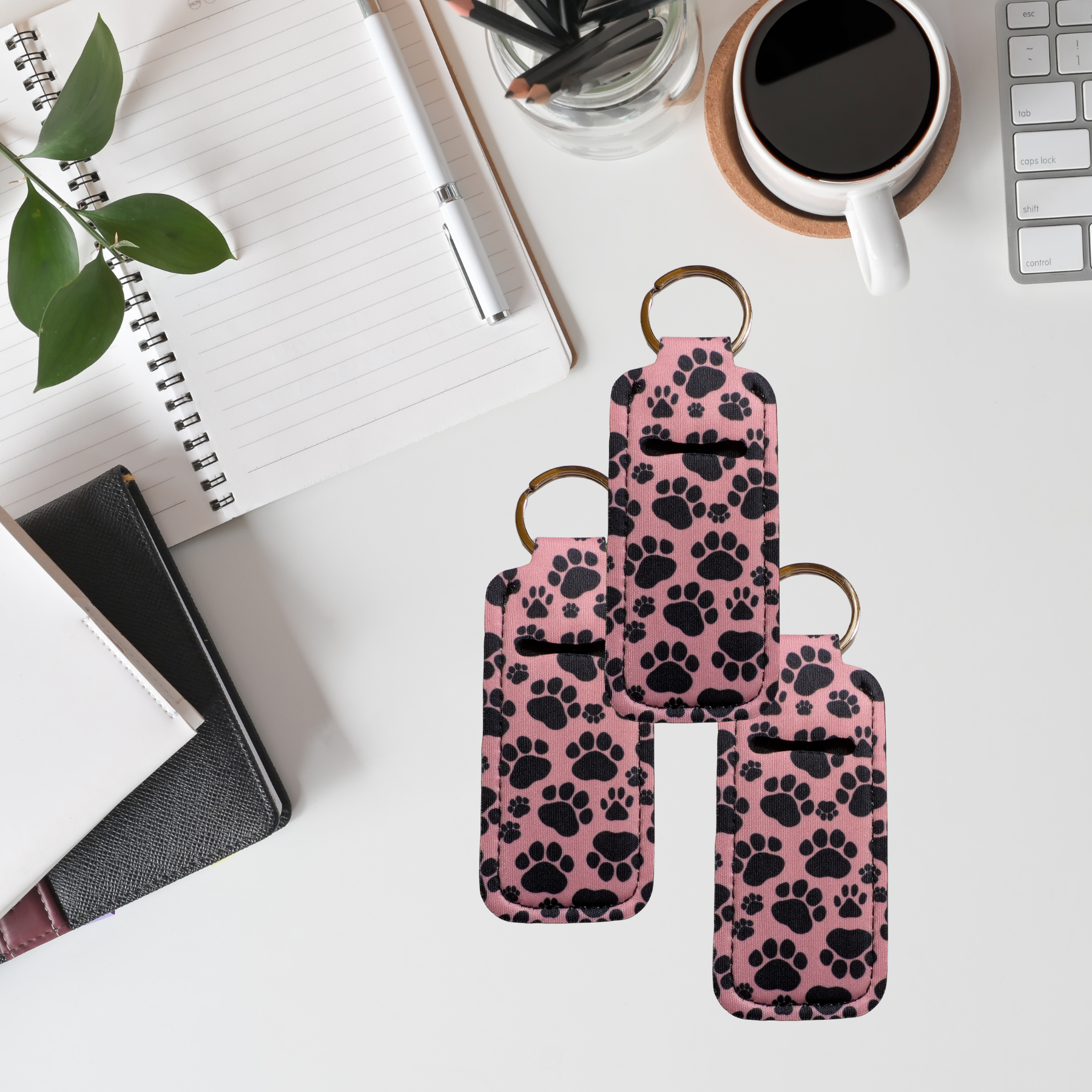 Pink phone case with black paw prints on a desk with office supplies.