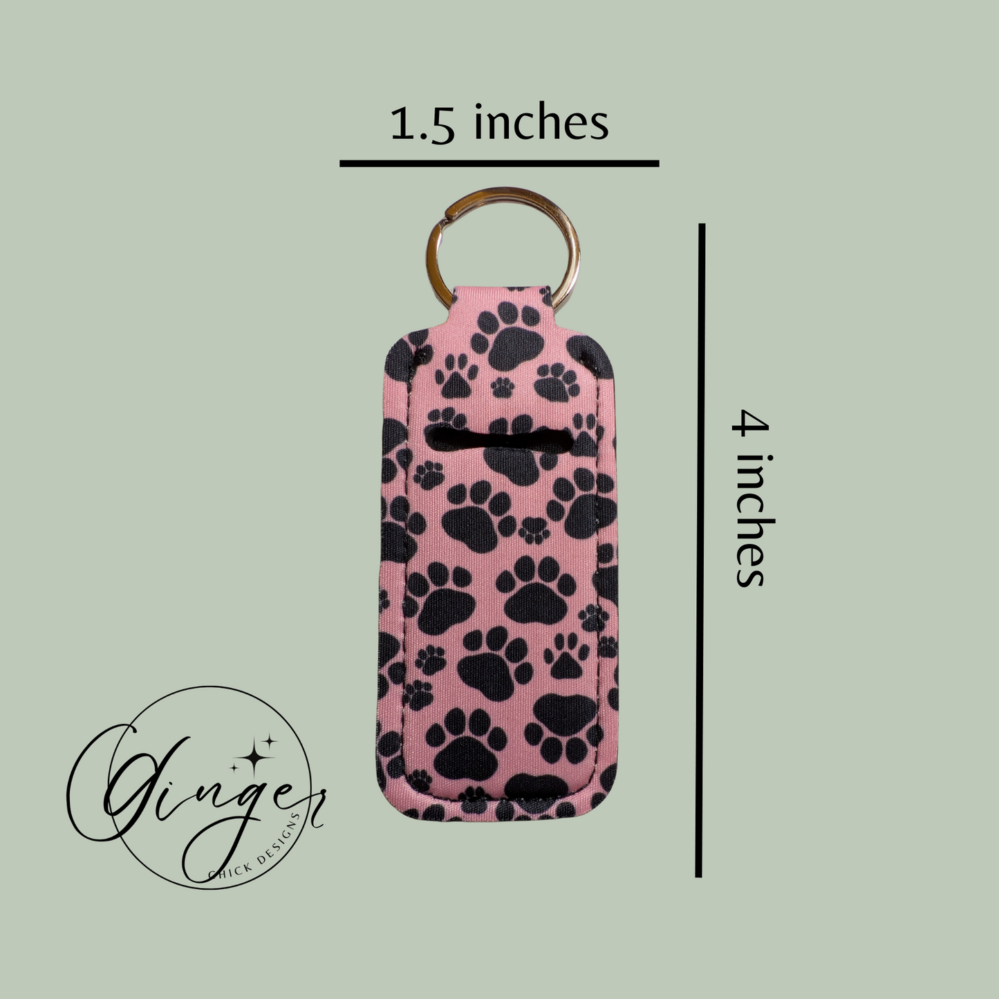 Pink keychain case with black paw prints and dimensions on a light green background