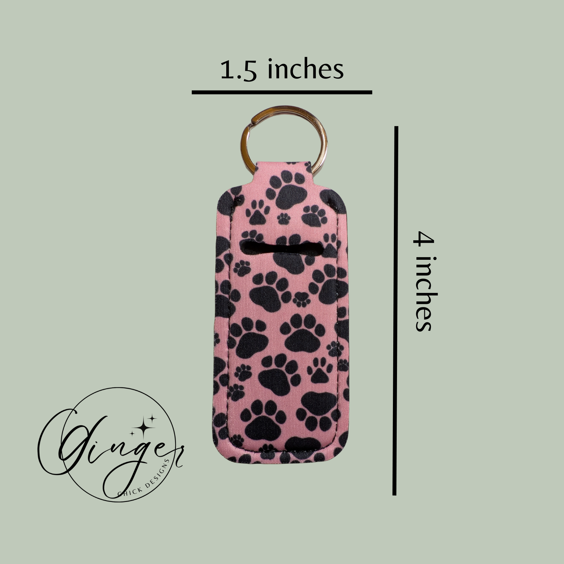 Pink keychain case with black paw prints and dimensions on a light green background