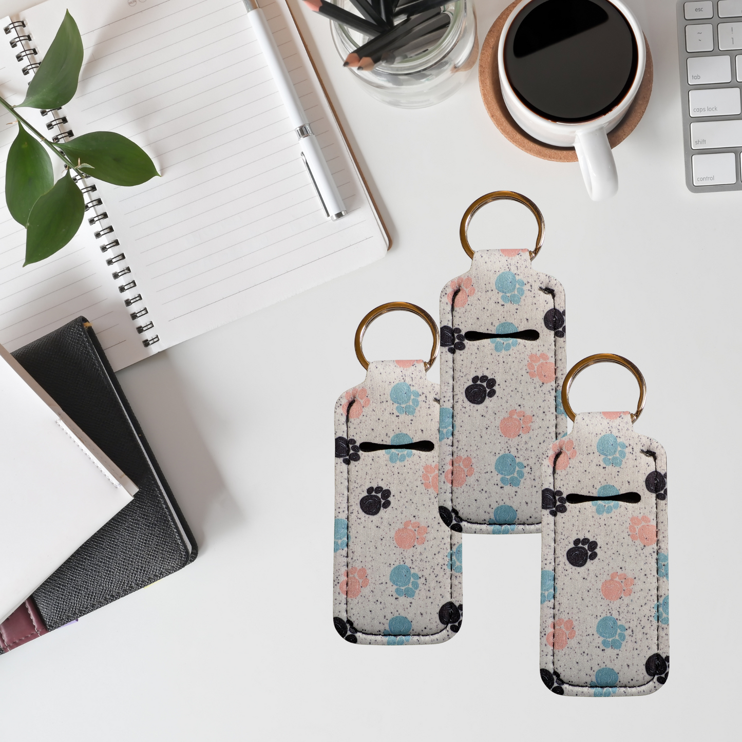 Two keychain pouches with paw print pattern on a desk with office supplies.
