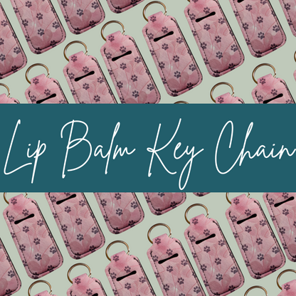 Pattern of pink lip balm keychains with paw prints on a green background, featuring text 'Lip Balm Key Chain'.