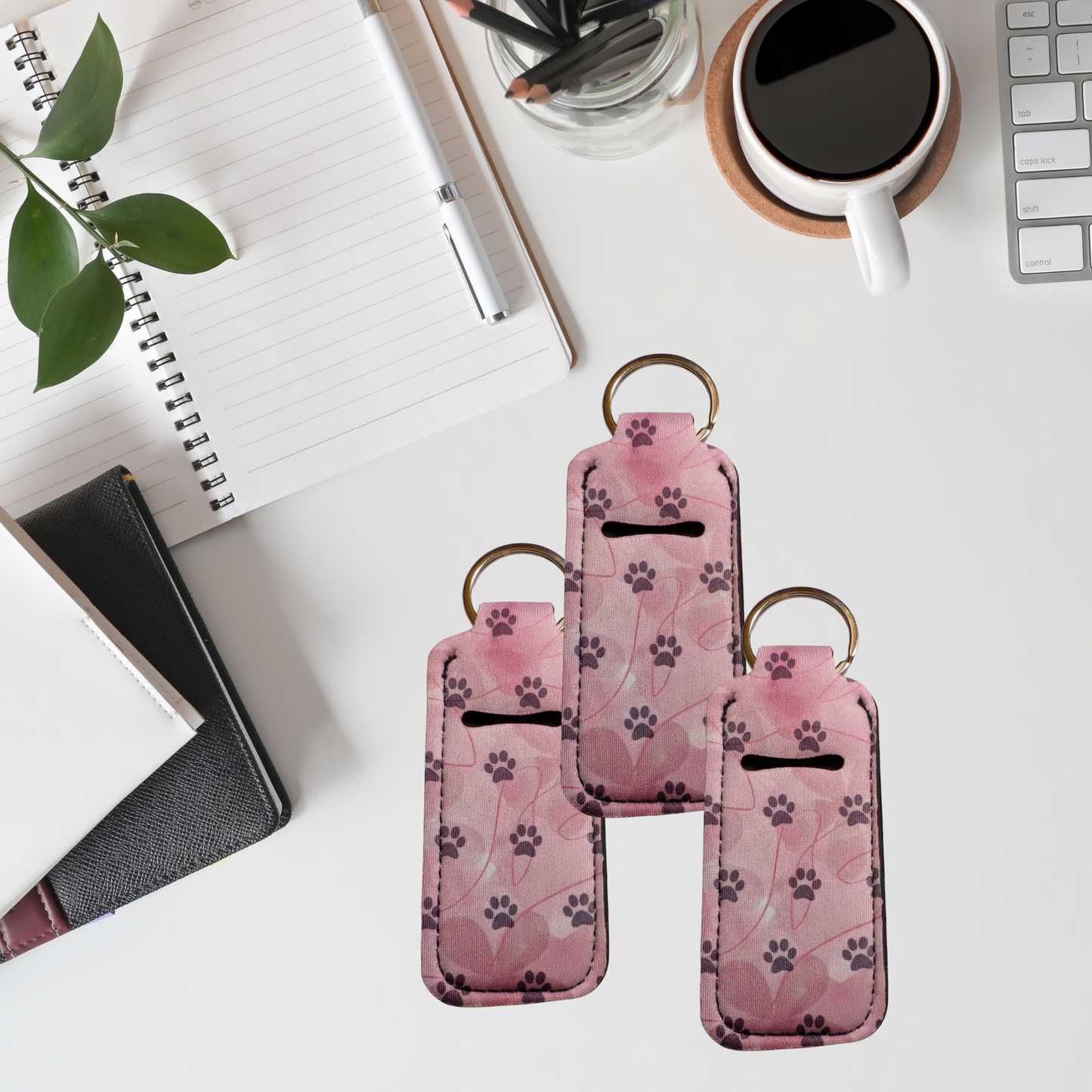 Pink keychain with paw print pattern on a desk with office supplies.