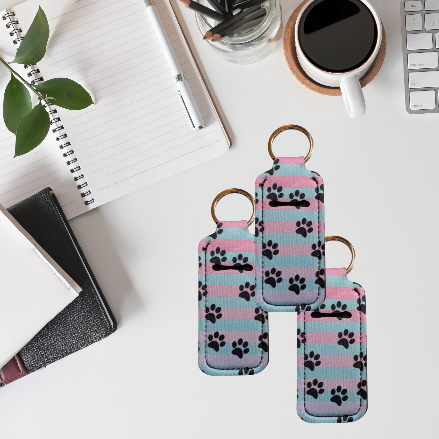 Keychains with paw pattern on a desk with a cup of coffee and notebook.