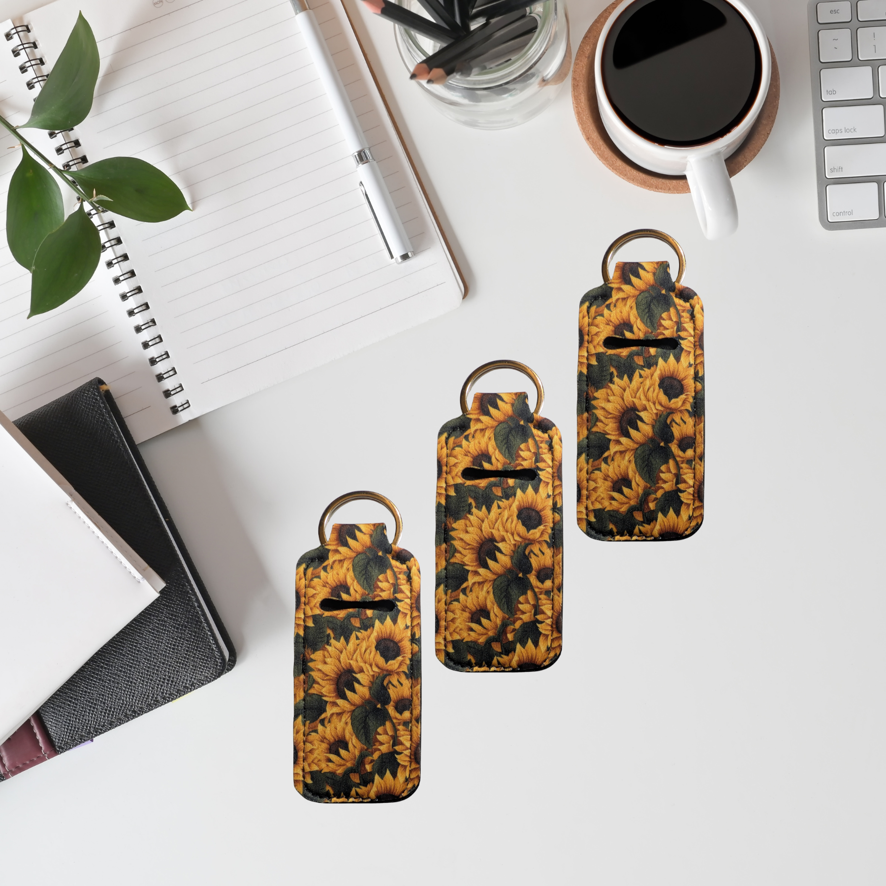 Sunflower-patterned keychain cases on a desk with office supplies.