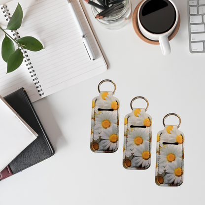 Three floral keychains on a desk with a notebook, coffee cup, and plant.